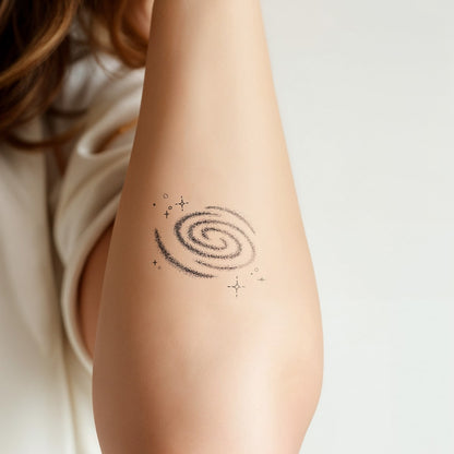 A woman's arm wearing a white cloth with a nebula tattoo on her forearm, on a white background - Wide Awake NYC 