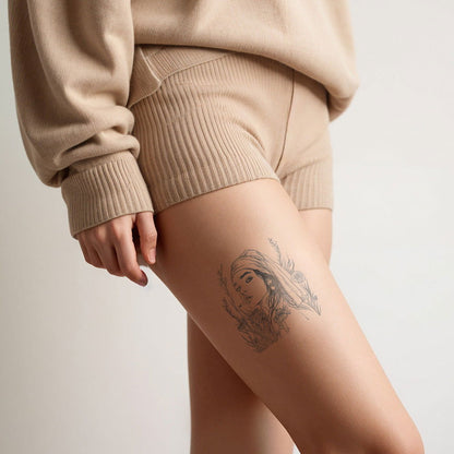 A Modern Vermeer tattoo adorns a woman's leg, paired with a cozy brown sweater - Wide Awake NYC